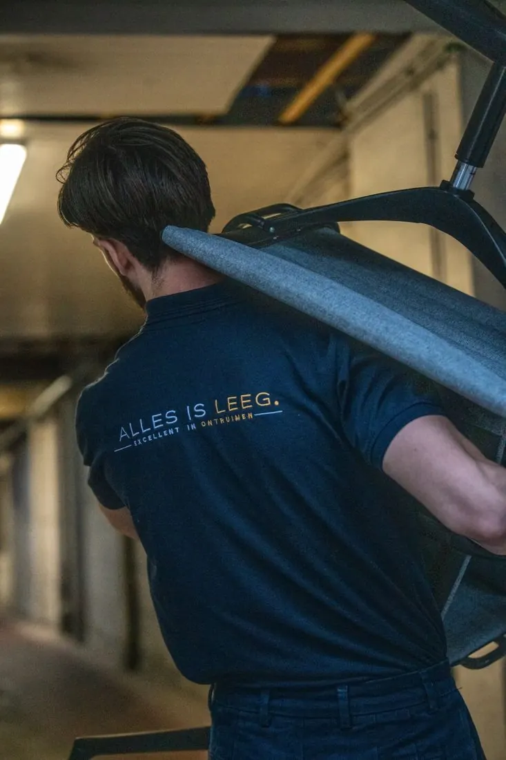 Medewerker van Alles Is Leeg draagt een stoel op zijn schouder